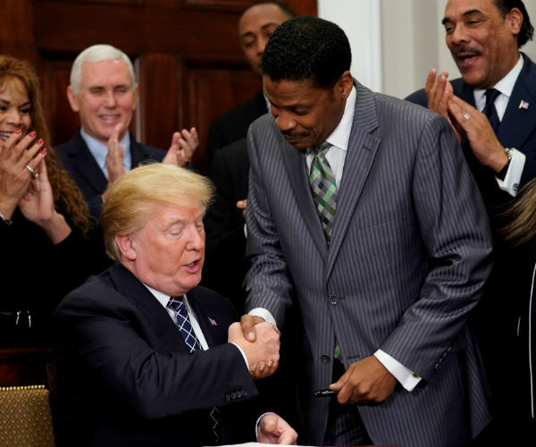 President Donald Trump shakes hands with Issac New...