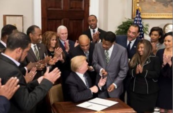 President Donald J. Trump hands a pen to Isaac New...